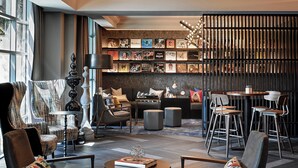 A modern lounge area with a mix of seating options, a bookshelf with various books, and a decorative wall with vertical slats. - Renaissance Los Angeles Airport Hotel (Los Angeles)