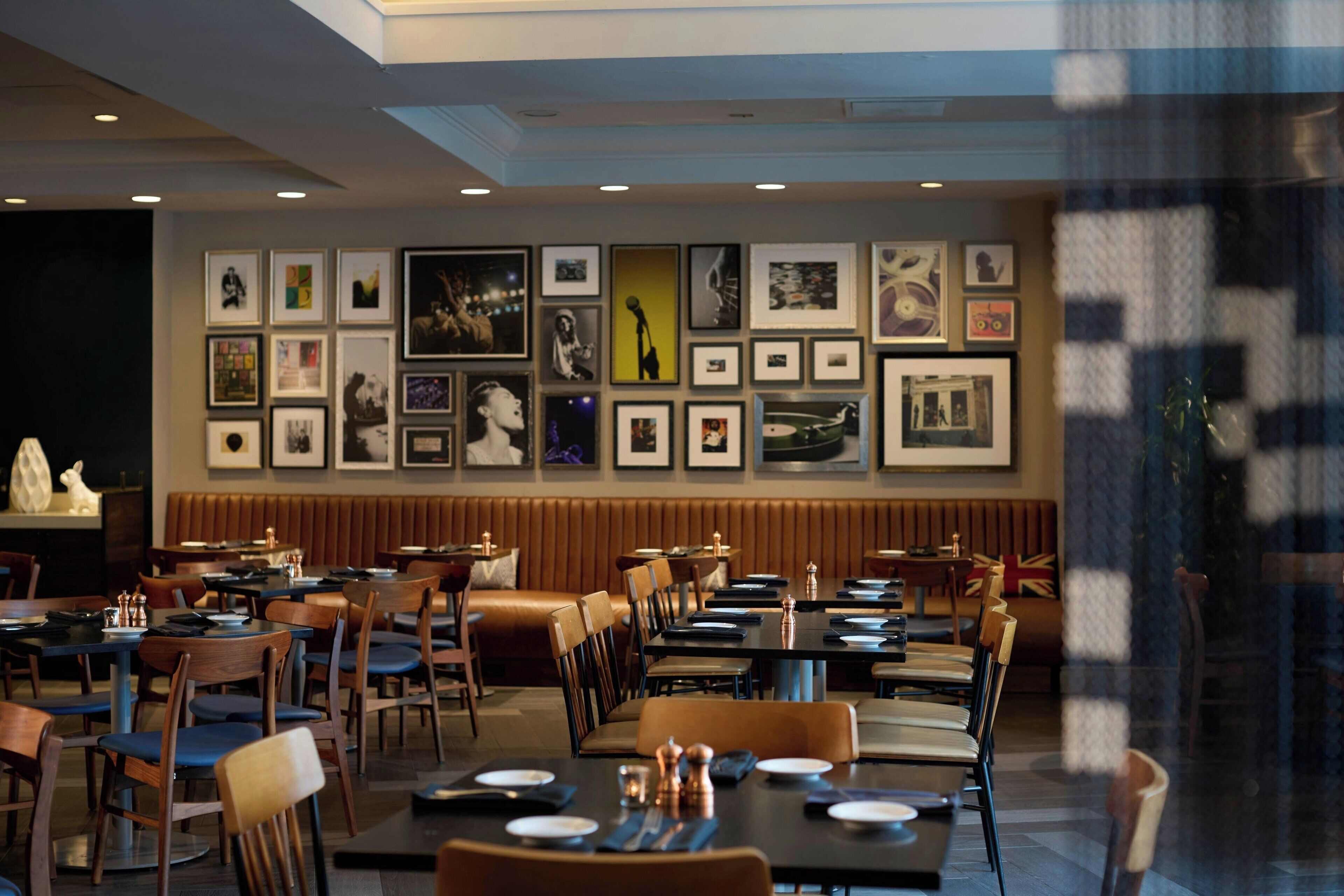 Un restaurant avec des banquettes et des tables, des œuvres d’art encadrées accrochées aux murs, et un drapeau britannique sur le mur du fond.