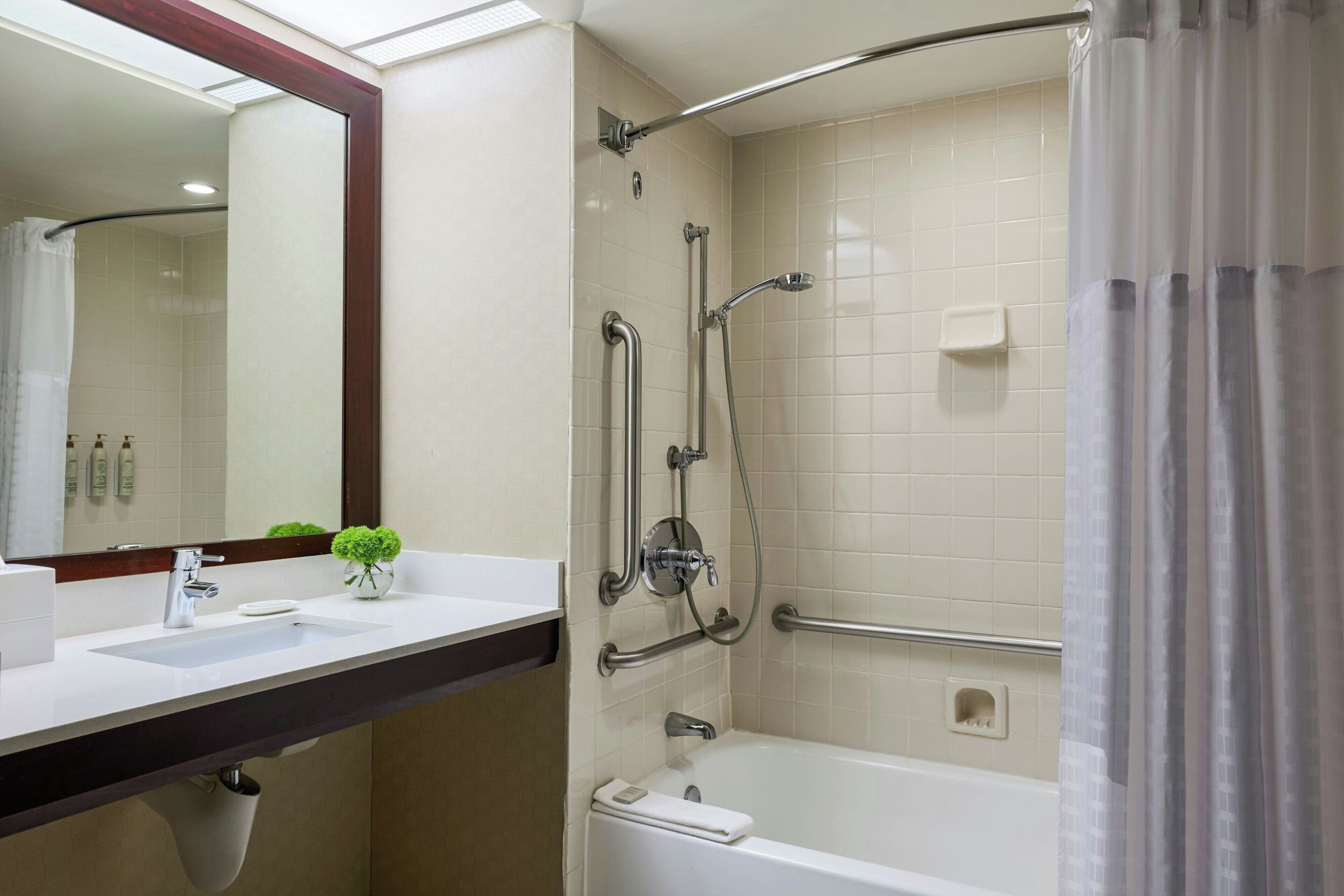 A bathroom with a white sink, mirror, and bathtub.