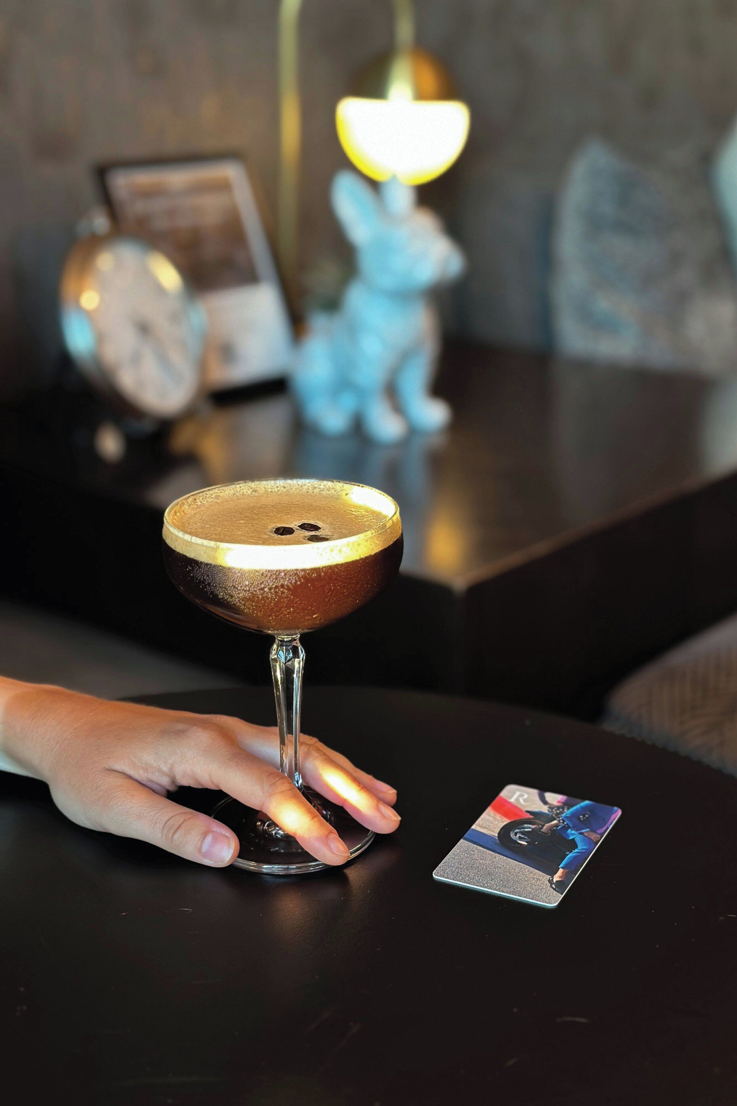 Un verre à cocktail sur une table, avec une carte à côté.