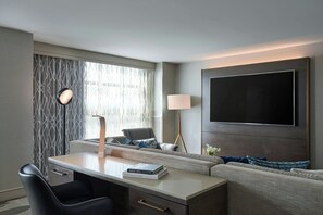 A modern hotel room with a desk, sofa, and a large TV mounted on the wall. - Renaissance Los Angeles Airport Hotel (Los Angeles)