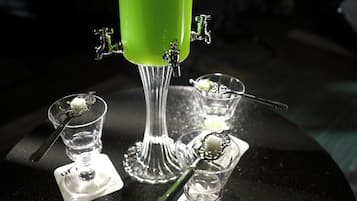 Un dispensador de bebidas verde con cuatro vasos, cada uno con una cuchara y un pequeño plato.