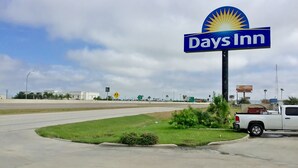 A Days Inn sign with a sun emblem, a parking lot, and a white truck. - Days Inn by Wyndham McAllen (McAllen)