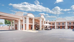 A multi-story motel with a central atrium, outdoor parking, and a clear sky. - Days Inn by Wyndham McAllen (McAllen)