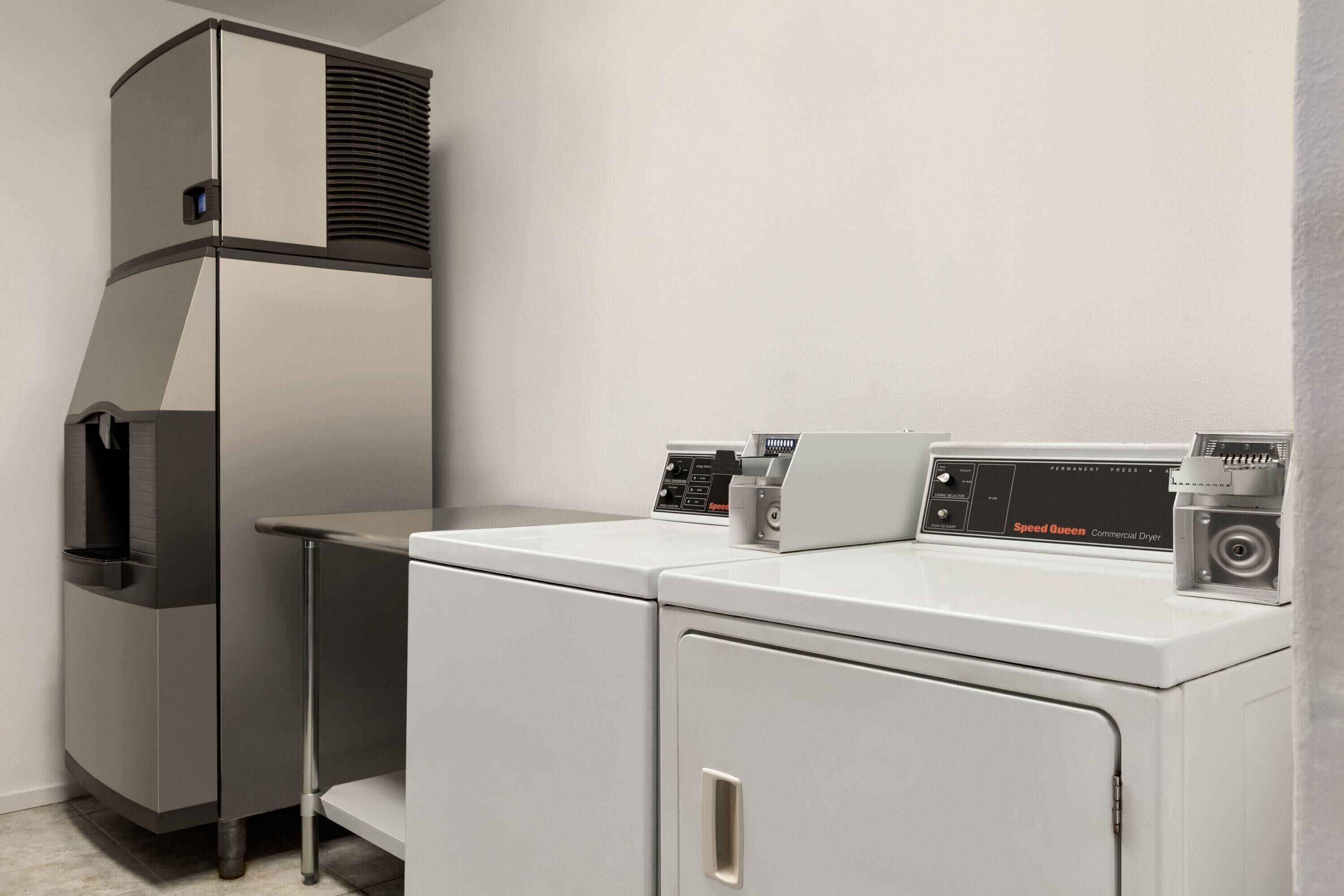 A compact laundry area with a front-loading washer and dryer, a built-in water heater, and a small sink.