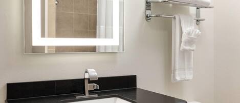 A modern bathroom with a black sink, a mirror, and a towel rack with towels.