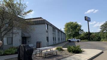 A stone building with a covered grill and picnic table, a Comfort Inn sign, and a white truck parked nearby.