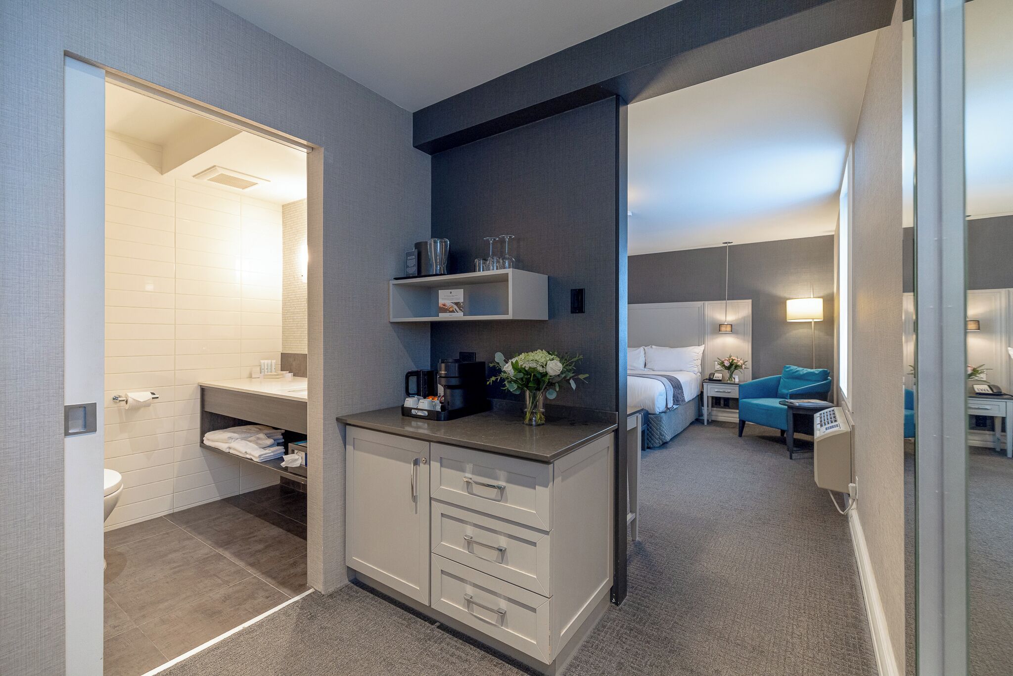 Une chambre d’hôtel moderne comprenant une salle de bain, un coin cuisine, un lit et un espace salon.
