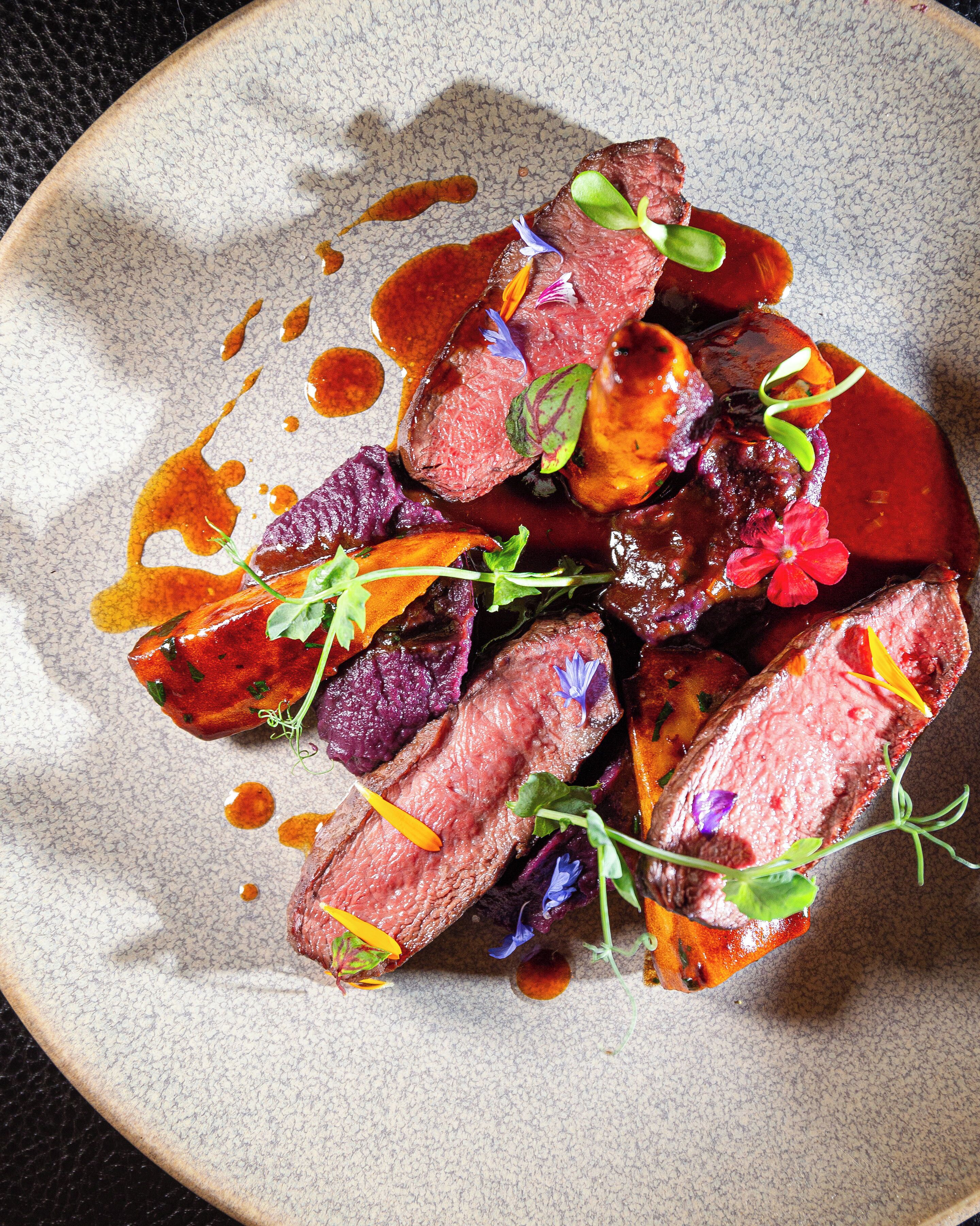 Ein Teller Essen mit geschnittenem Fleisch, Gemüse und Soße.