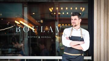 Um chef em frente a um vitrô do restaurante com o nome "BOULAY BISTRO A BORÉA" visível.