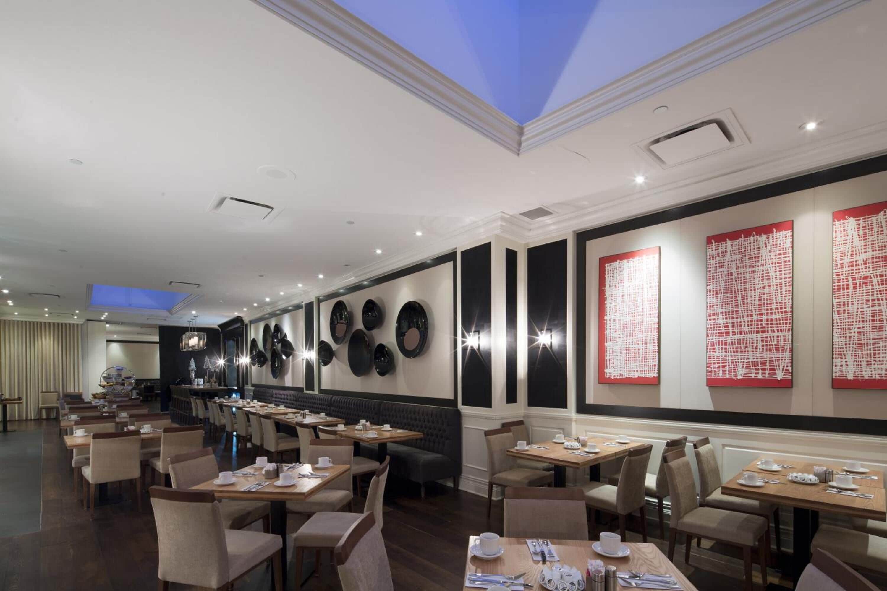 Un restaurante con varias mesas y cabinas, techo azul y decoración en las paredes.