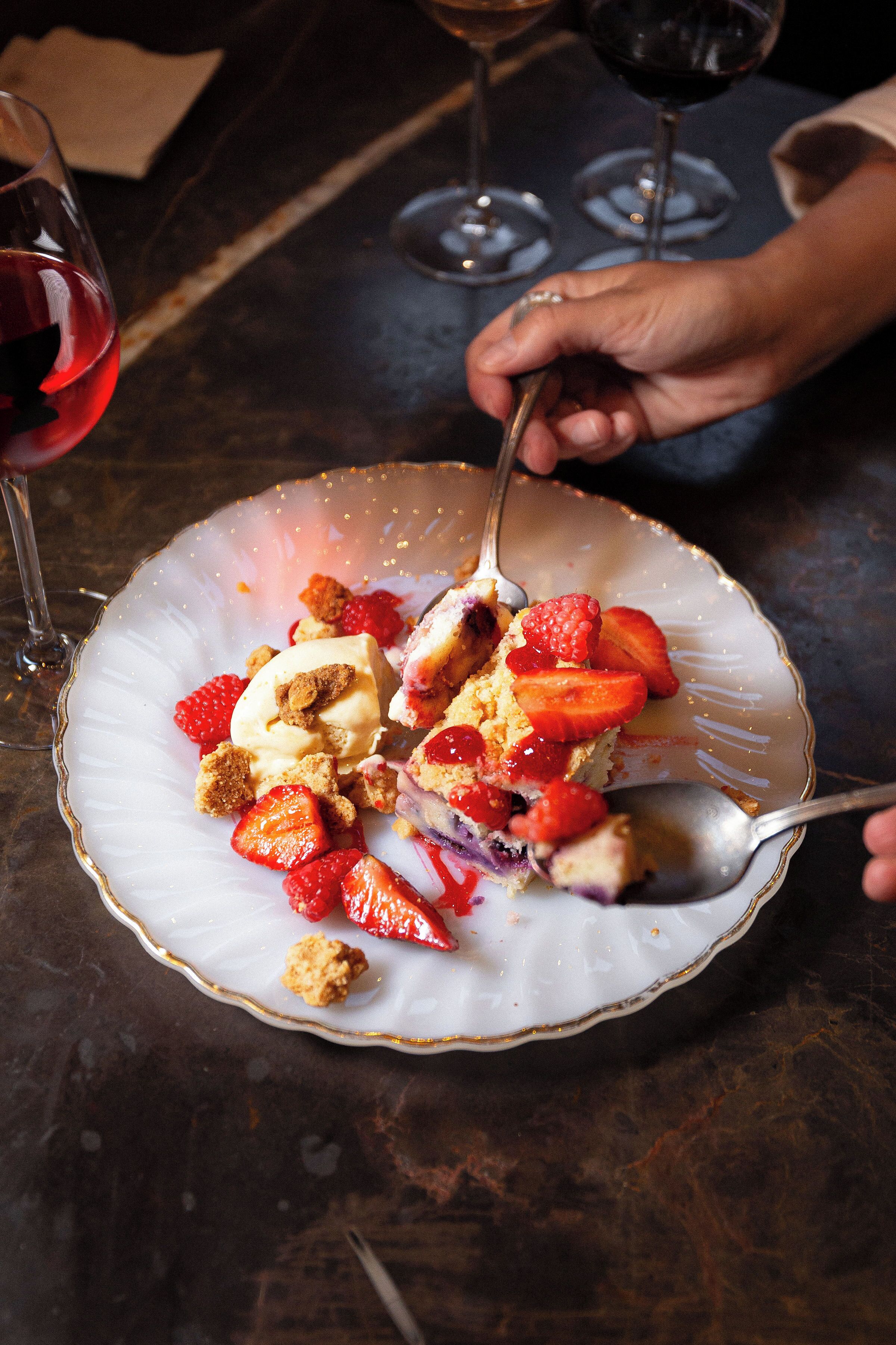 A dessert plate with strawberries and a scoop of ice cream on a table.