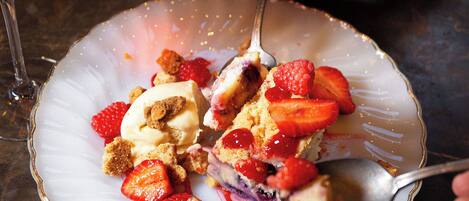 A dessert plate with strawberries and a scoop of ice cream on a table.