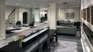 A modern hotel lobby with a long reception desk, seating area, and a patterned floor.