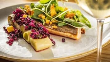 A plate of food with a glass of white wine on a wooden table.