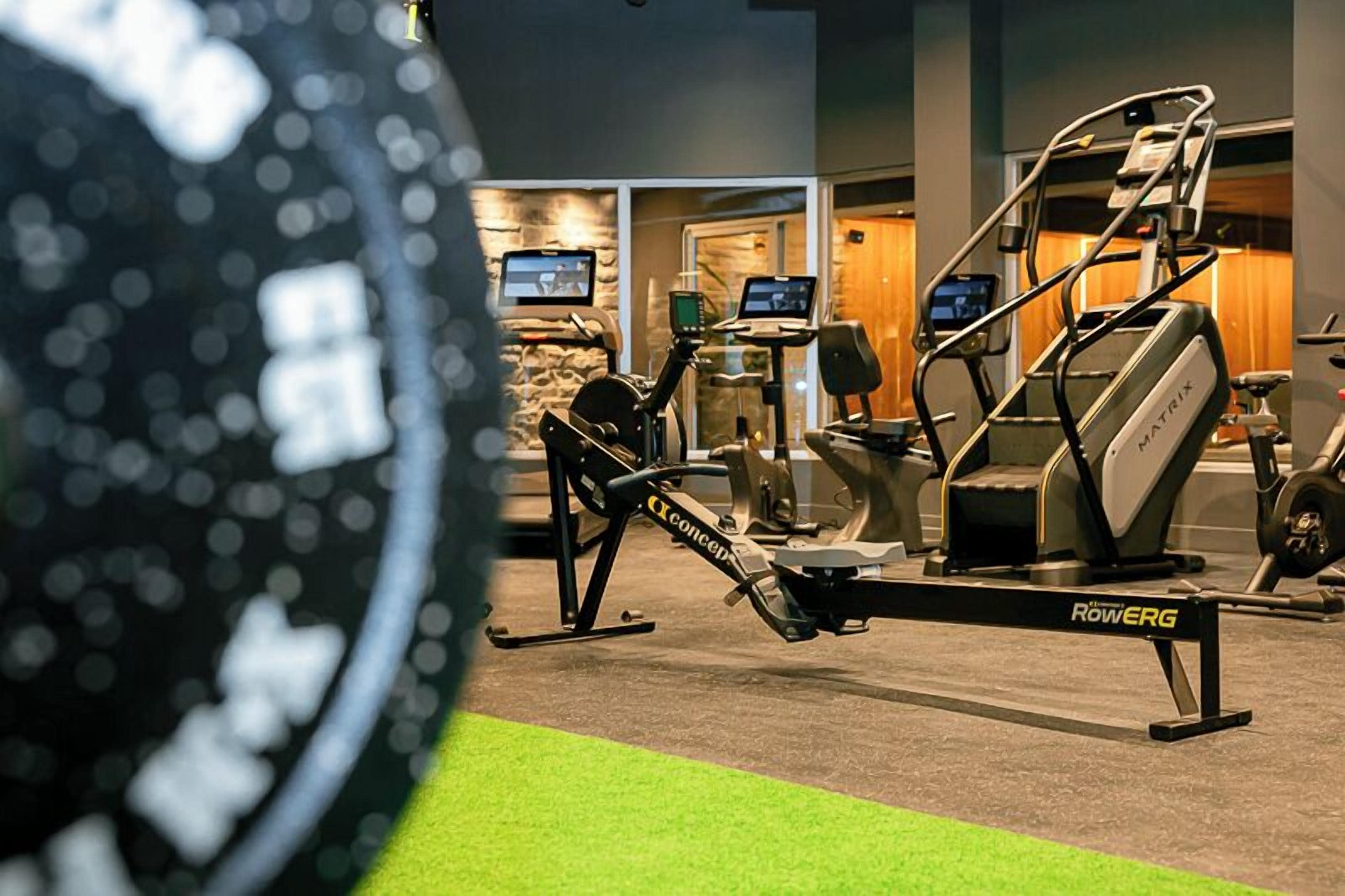 Une salle de sport équipée de matériel d’exercice, notamment un rameur et un appareil de musculation elliptique.