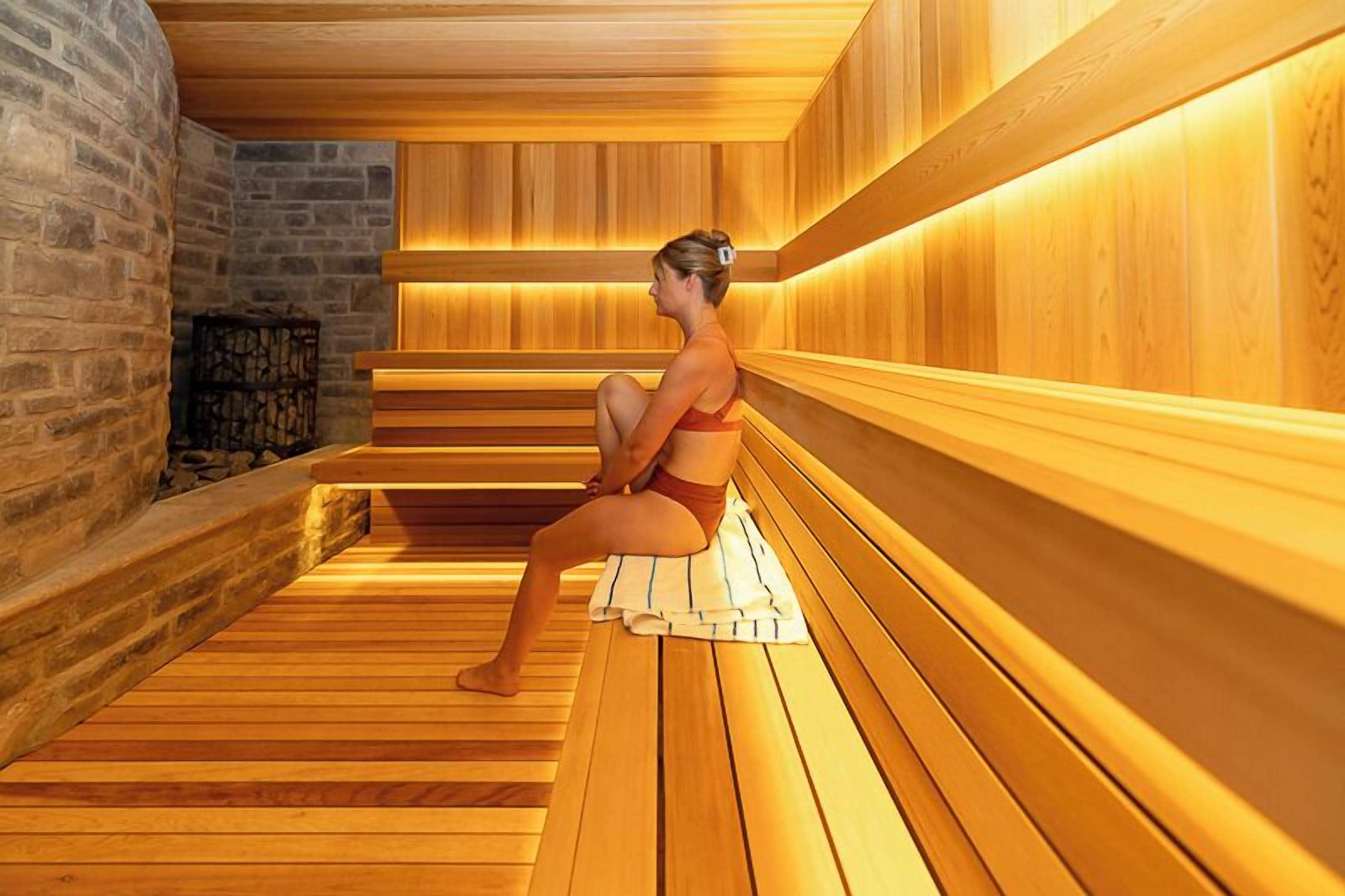 A sauna with wooden benches and a stone wall.