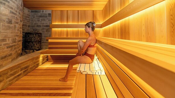A sauna with wooden benches and a stone wall.