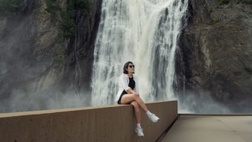 Una persona sentada sobre un borde de hormigón con una cascada al fondo.