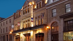 Un hôtel historique à la façade classique, orné de nombreux drapeaux, et doté d’une entrée imposante surmontée d’un auvent.