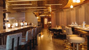 A restaurant interior with a long counter, multiple tables, and chairs.
