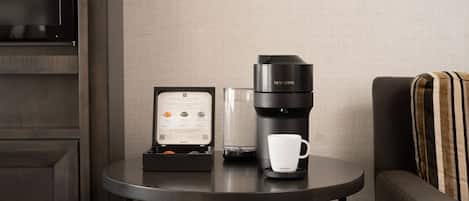 A compact coffee maker on a small table with a coffee cup and a menu.