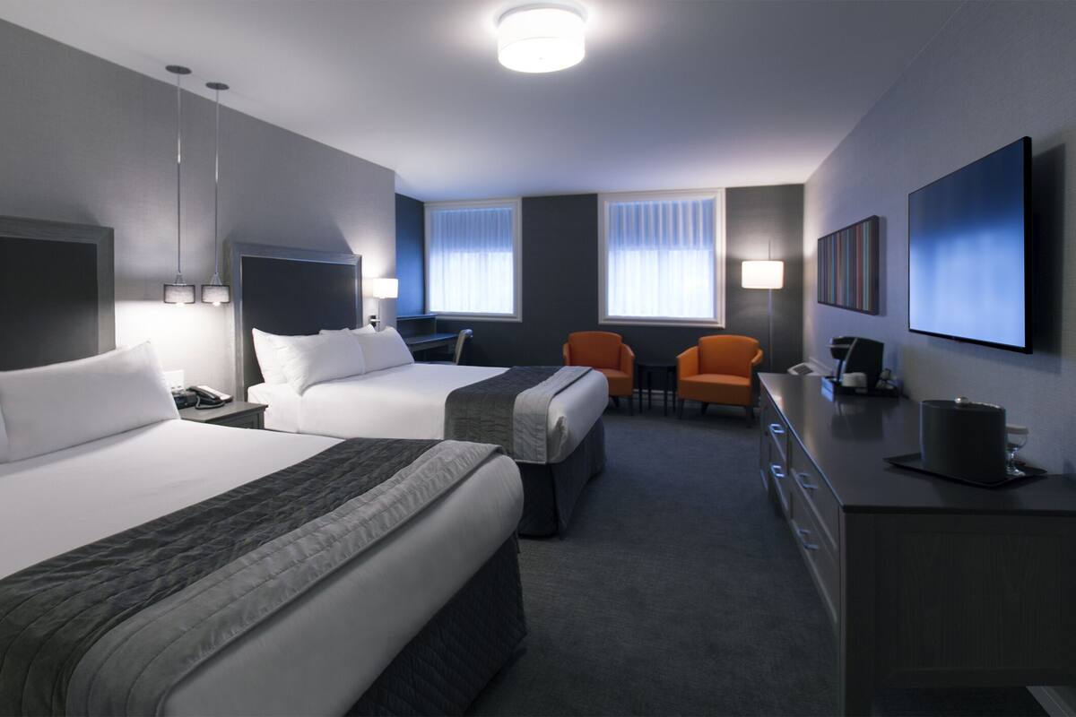 Une chambre d’hôtel avec deux lits, un bureau, une chaise et une télévision.