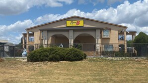 A Super 8 by Wyndham hotel with a large sign, arched entrance, and a fenced front yard.
