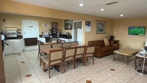 A compact living space with a dining area, a sofa, a TV, and a kitchenette. - Super 8 by Wyndham Decatur Texas (Decatur)