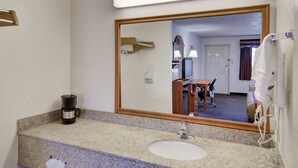 A hotel bathroom with a granite countertop, a sink, a mirror, a hairdryer, and a coffee maker. - Super 8 by Wyndham Decatur Texas (Decatur)