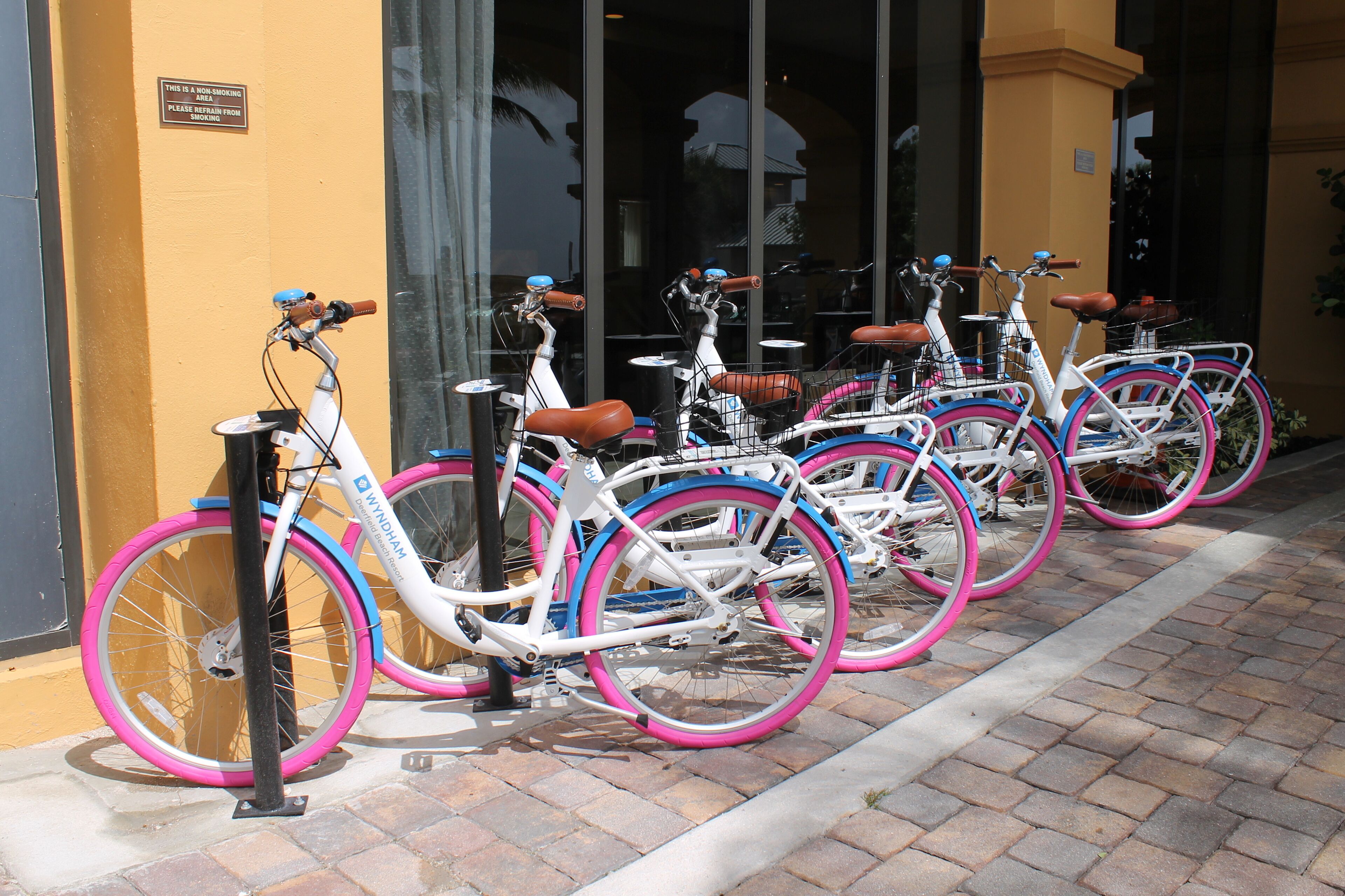 Varias bicicletas estacionadas frente a un edificio con un letrero que indica prohibido fumar.