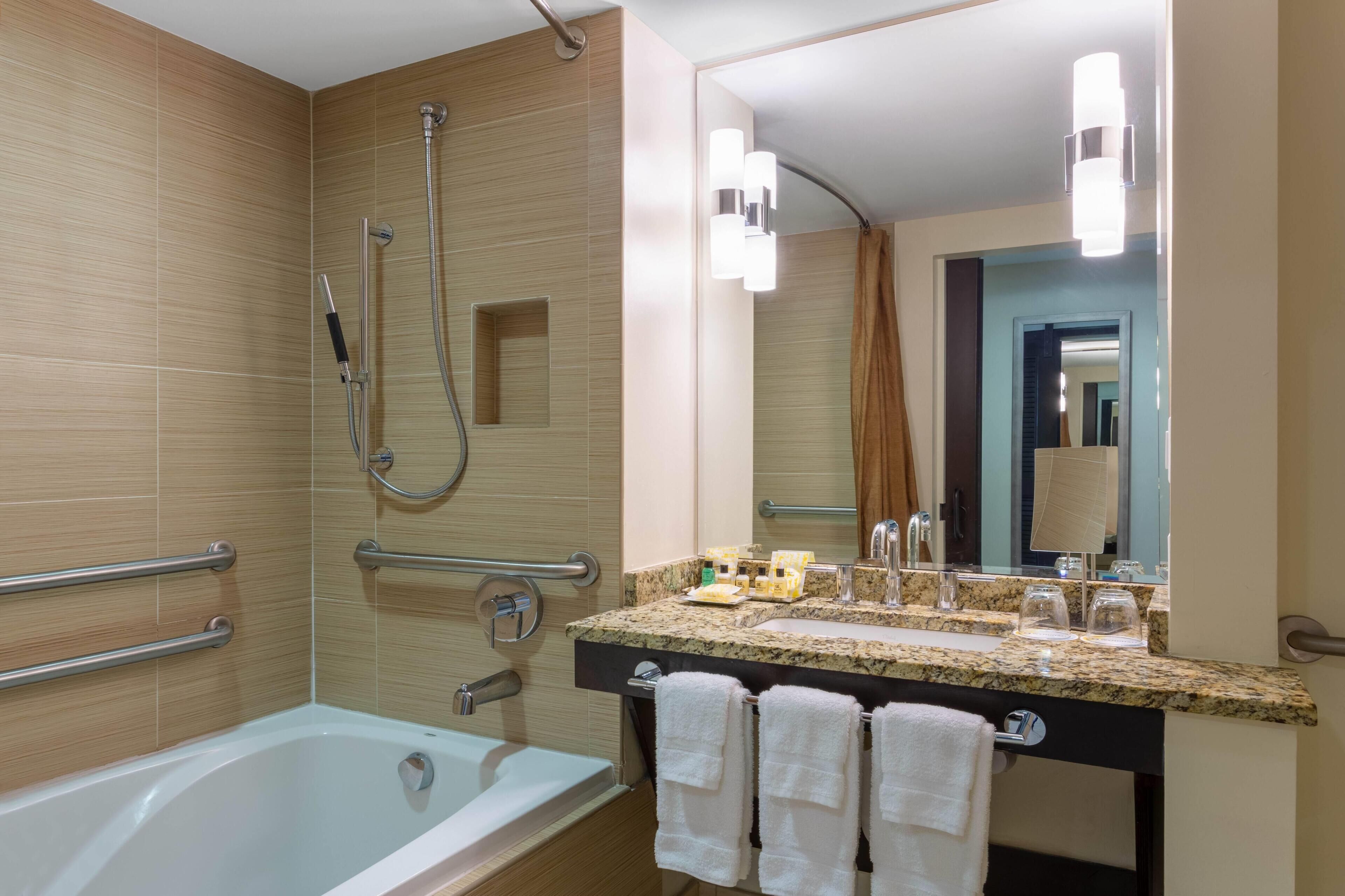 Un baño moderno con bañera, ducha y tocador con espejo.