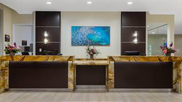 Een receptie met marmeren balies, een groot abstract schilderij en twee wandlampen.