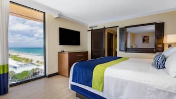 Habitación de hotel con una cama grande, televisión, armario y vista a la playa.