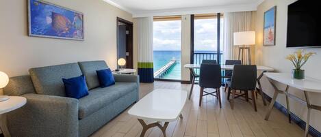 Une chambre d’hôtel avec un balcon, un canapé, une table à manger et un téléviseur.