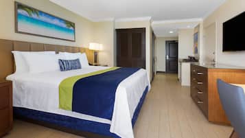 Una camera d'albergo con un letto, una scrivania, una televisione e un ingresso che dà su una cucina.