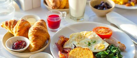 A breakfast setting with croissants, eggs, bacon, toast, and a variety of spreads.