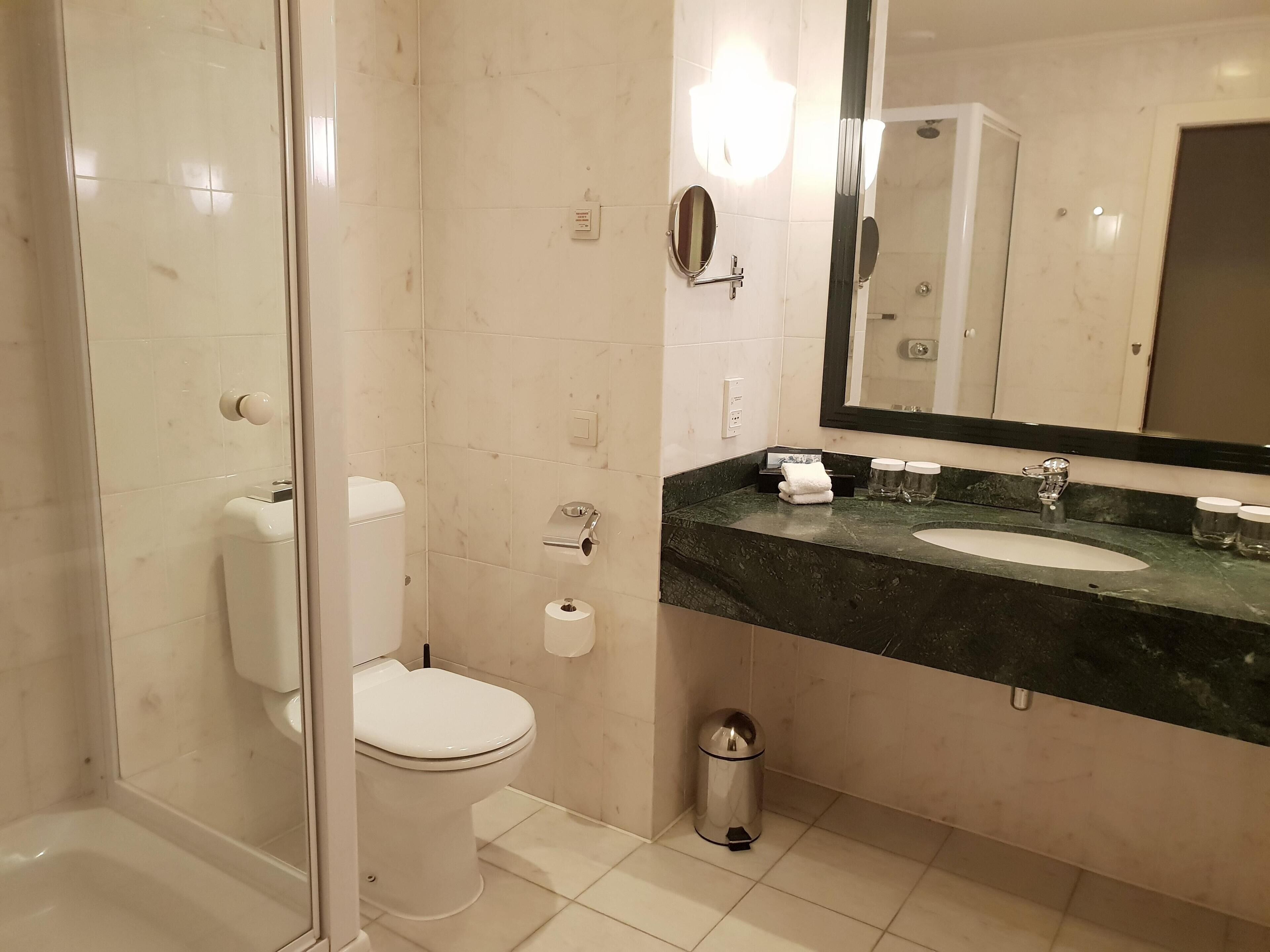 A bathroom with a toilet, sink, and mirror.