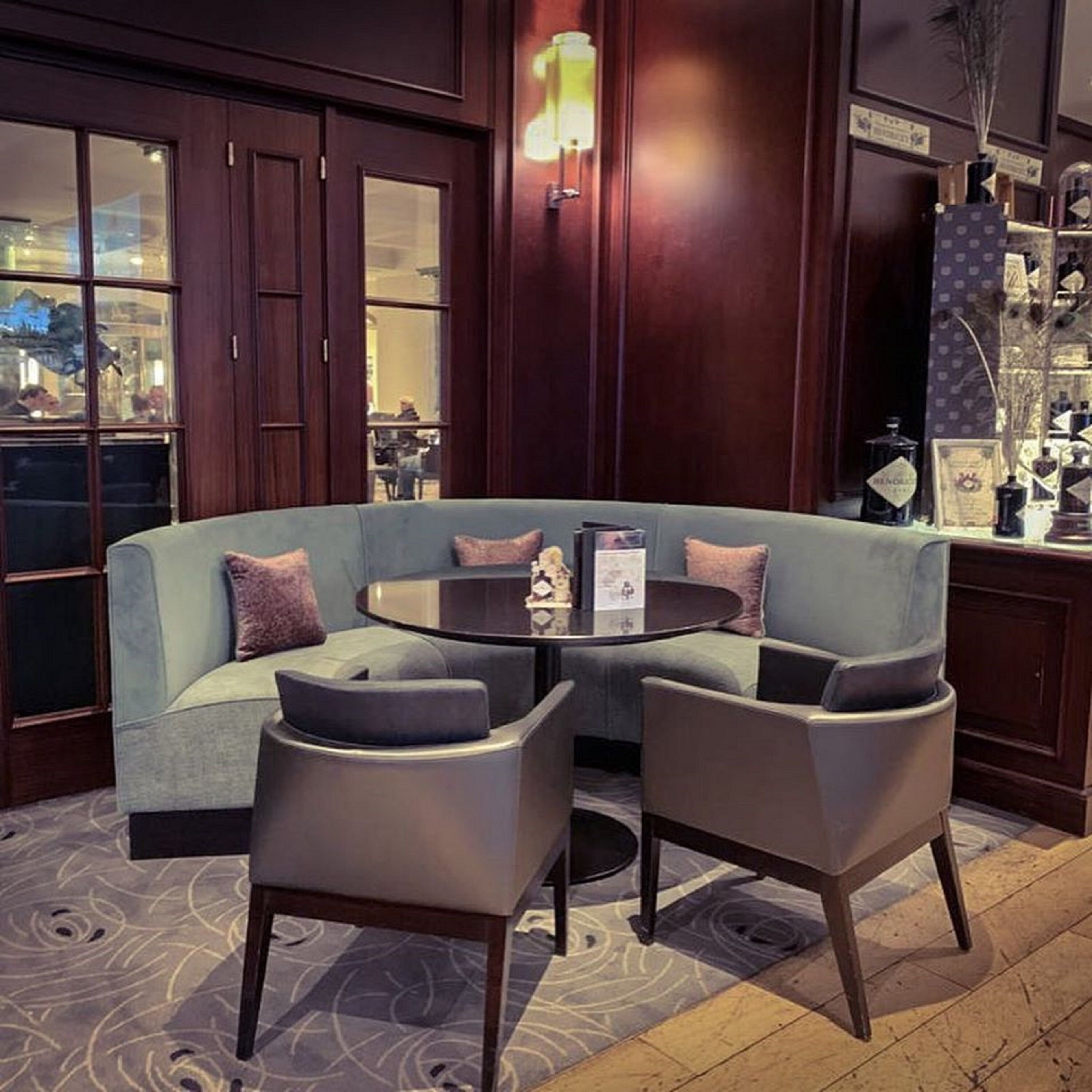 A modern lounge area with a curved sofa, two armchairs, and a round table.