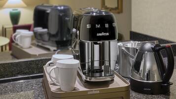 A coffee station with a coffee maker, a kettle, and two mugs on a countertop.