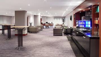 A hotel lobby with seating areas, a reception desk, and a bar.