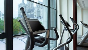 Palestra interna con cyclette e un'ampia finestra che si affaccia su un edificio storico.