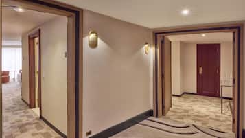 Un couloir d’hôtel avec des revêtements de sol en moquette, des encadrements de porte en bois et des luminaires fixés au mur.