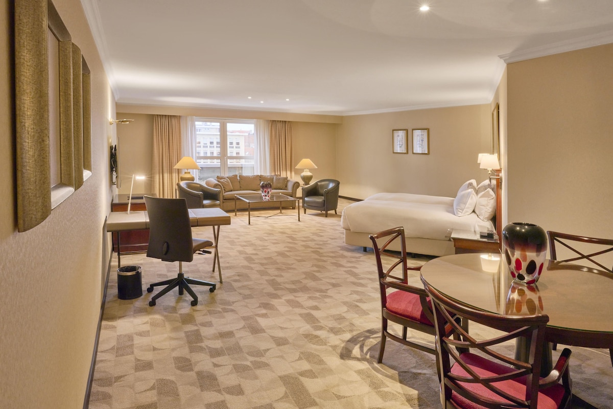 Una habitación de hotel con una cama, un escritorio, una silla, una mesa de comedor y un sofá.