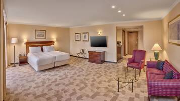 Een hotelkamer met een tweepersoonsbed, een televisie, een bureau, een stoel en een bank.