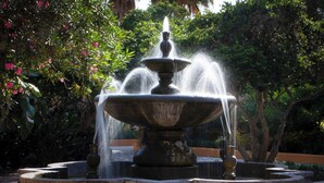 Ein Steinfountain mit Wasserstrahlen in einem Garten.
