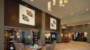 Eine großzügige Lobby mit einer Rezeption, einer Sitzecke und einer Bar.