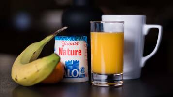 Un verre de jus d’orange, une tasse blanche et un pot de yaourt.
