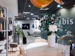 A modern interior with a wall-mounted guitar display, a white vase with flowers, and a 'bis' sign. - ibis Caen Centre (Caen)