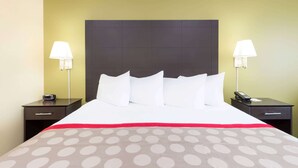 A hotel room with a large bed, two bedside tables, a nightstand, and a lamp on each side.